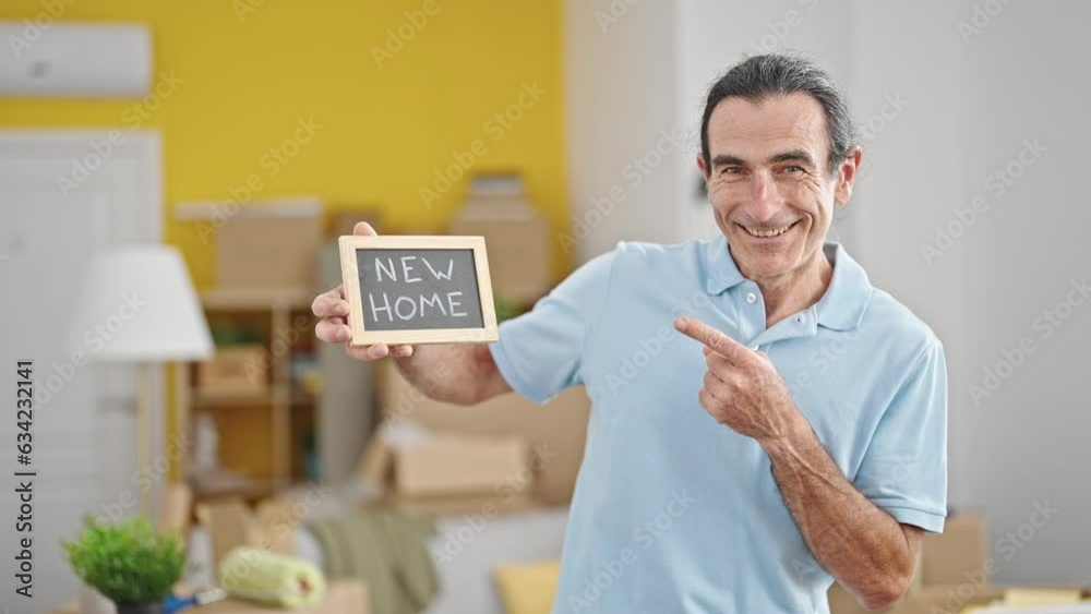 Middle age man smiling confident pointing to blackboard at new home Middle age man smiling confident pointing to blackboard at new home