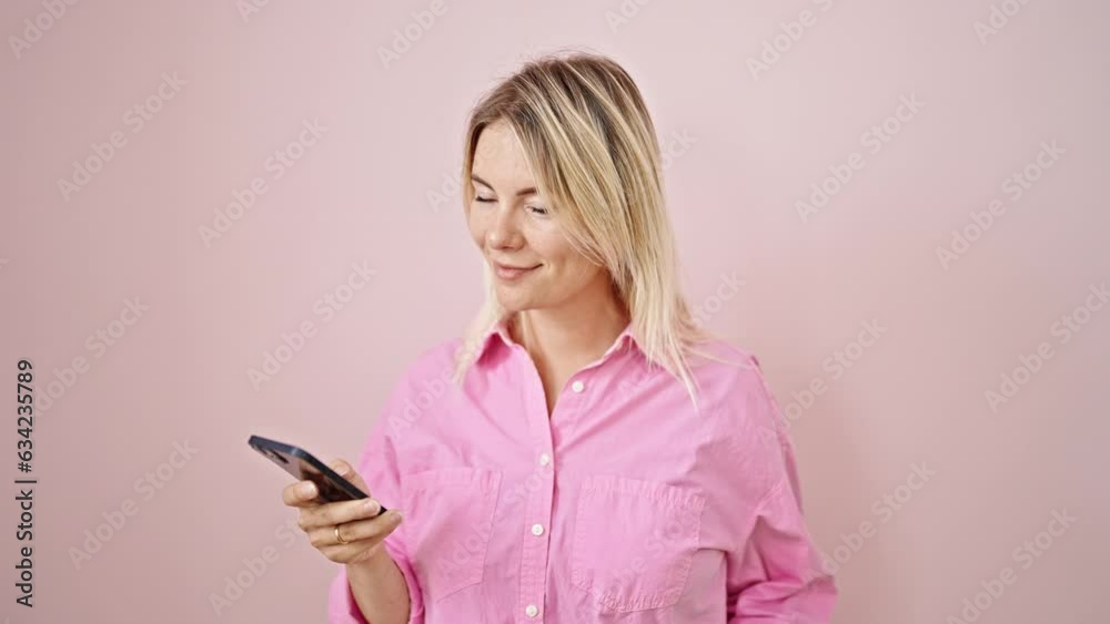 Young blonde woman using smartphone smiling over isolated pink background Young blonde woman using smartphone smiling over isolated pink background