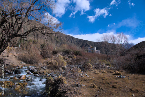 PAISAJE DE MONTAÑA CON UN ARROYO DE PIEDRA Y UNA CASA 