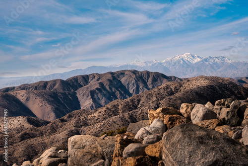 2023-01-27 SNOW COVERED MOUNTAINS AND ROLLING TERRAIN FROM INSDIE JOSHUA TREE NATIONAL PARK WITH A NICE BLUE SKY photo