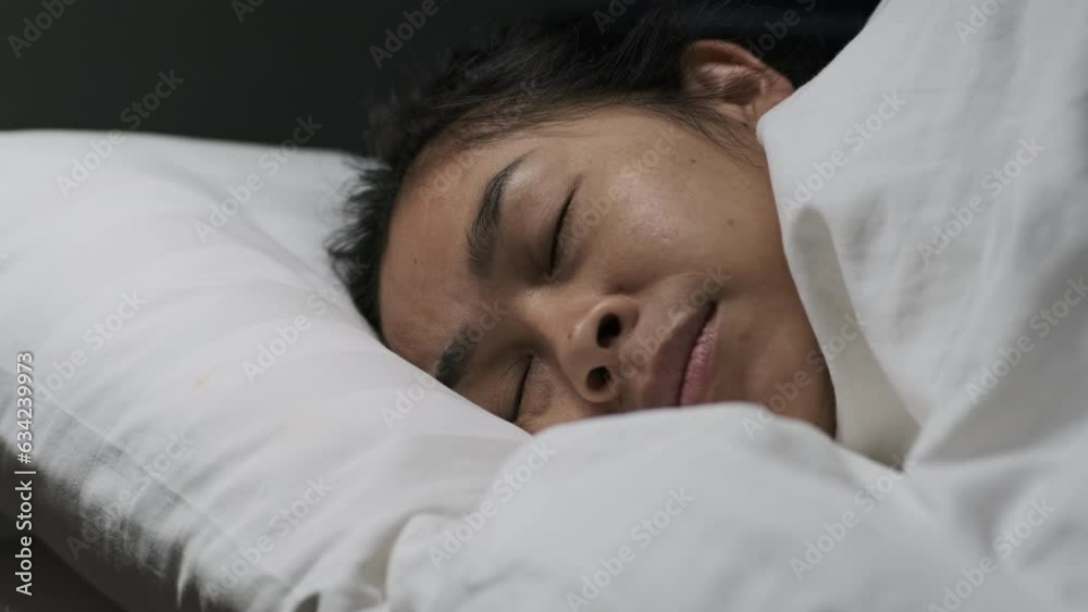 Asian woman resting covered with blanket on white sheets in bedroom. Woman sleeping. Peaceful woman lying in bed and keeping eyes closed while covered with blanket. Asian woman resting covered with blanket on white sheets in bedroom. Woman sleeping. Peaceful woman lying in bed and keeping eyes closed while covered with blanket.