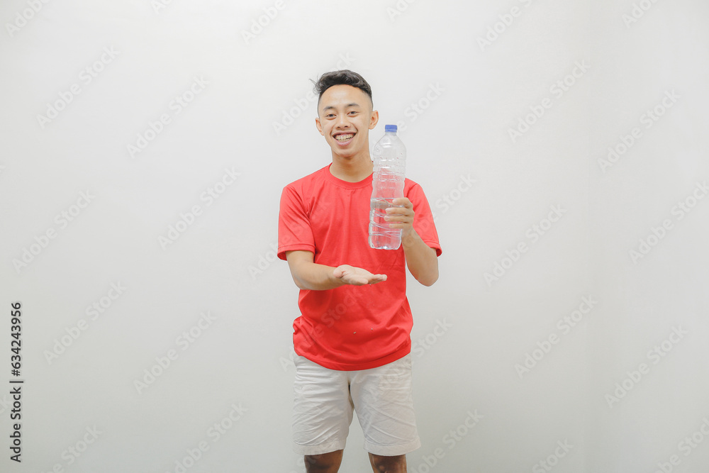 a young man wearing a red shirt on a white background is carrying a bottle of mineral water a young man wearing a red shirt on a white background is carrying a bottle of mineral water