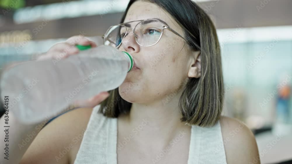 Young beautiful hispanic woman drinking bottle of water at the airport Young beautiful hispanic woman drinking bottle of water at the airport