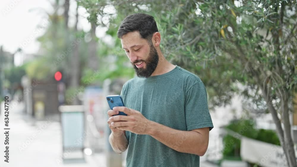 Young hispanic man using smartphone smiling at park Young hispanic man using smartphone smiling at park