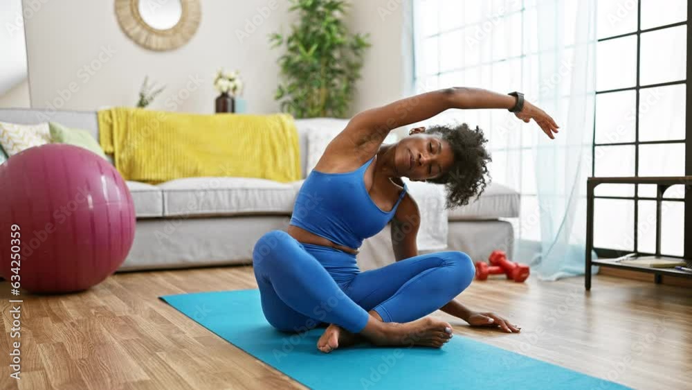 African american woman wearing sportswear stretching back at home African american woman wearing sportswear stretching back at home