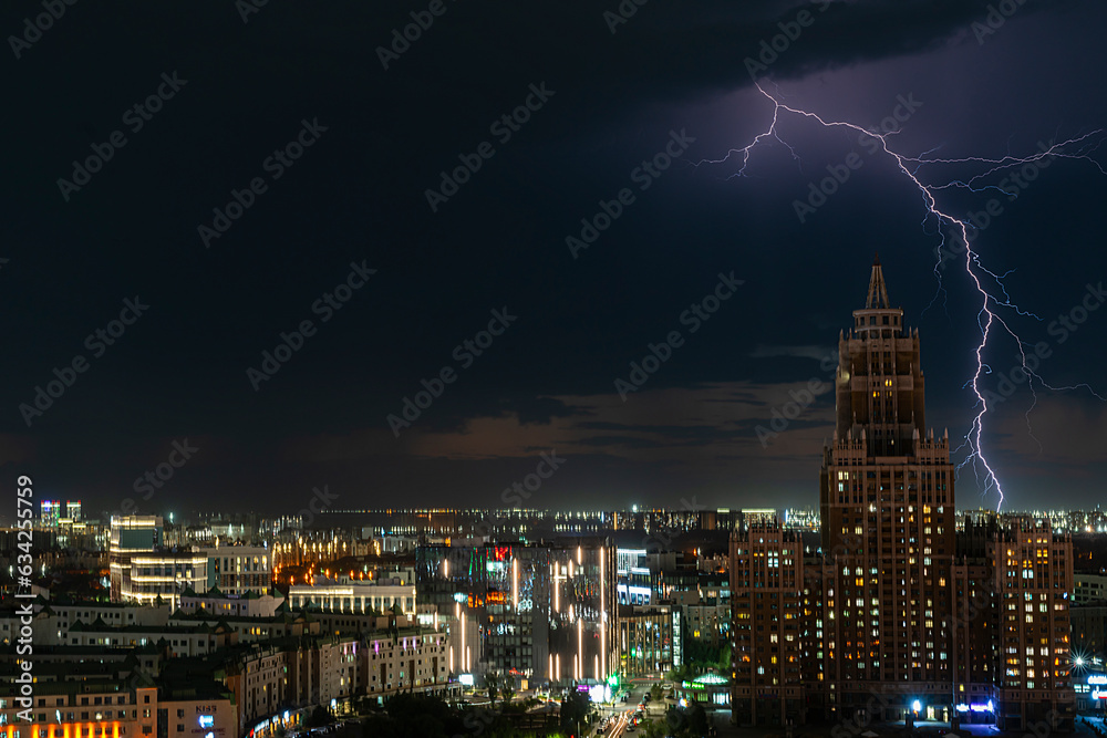 Fototapeta premium Astana, Kazakhstan, August, 2023. Night view of the skyscraper of the central street of the capital during a thunderstorm with lightning.