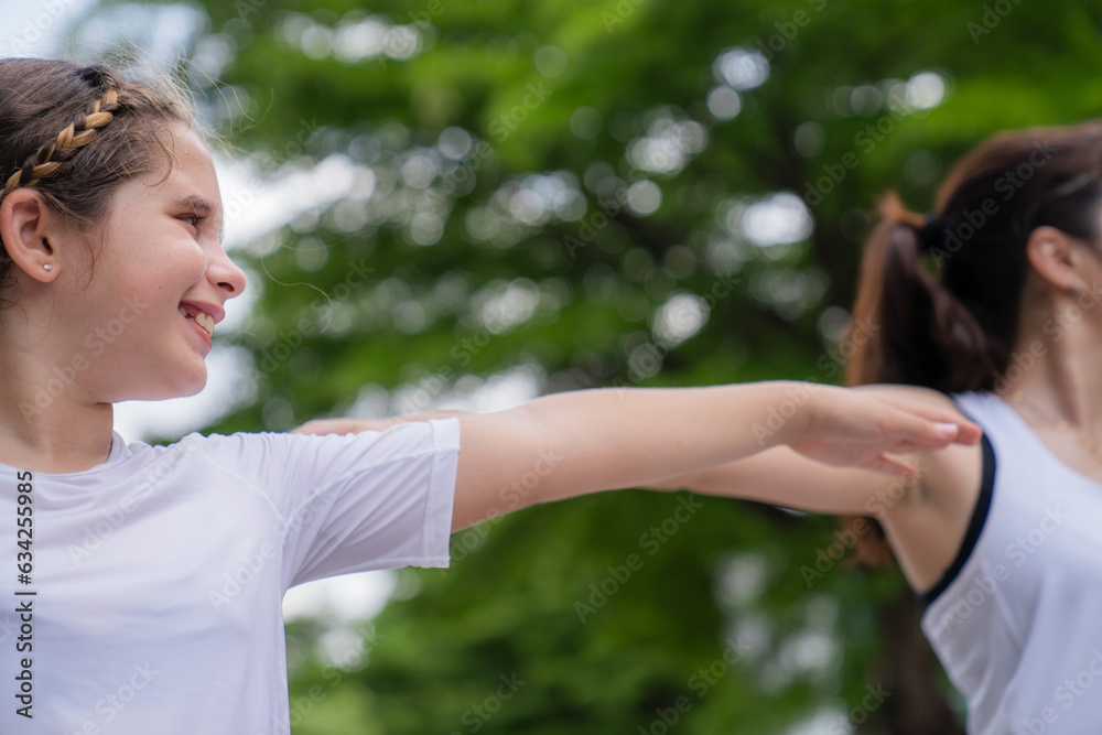 A happy girl exercising training in yoga and looking at the female instructor next to her in the park ,text space A happy girl exercising training in yoga and looking at the female instructor next to her in the park ,text space