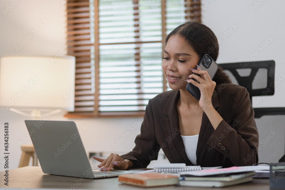 Young African woman using smartphone with laptop working at office, African American working online from home. Young African woman using smartphone with laptop working at office, African American working online from home.
