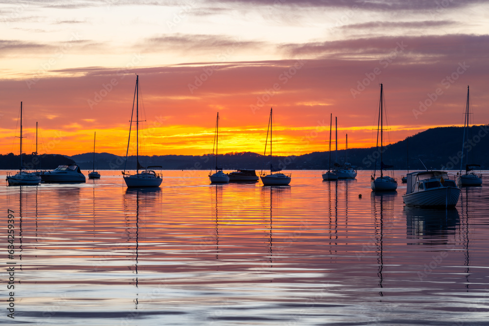 Sunrise over the water with boats, reflections and high cloud
