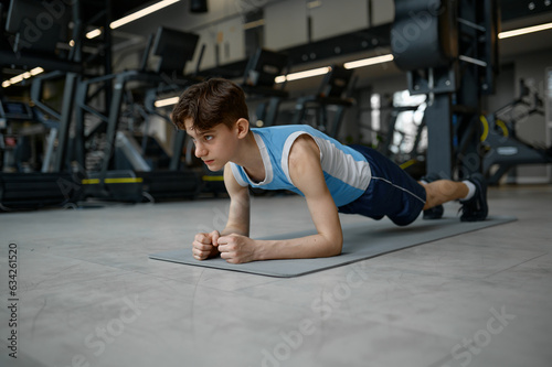 Teenager sport boy standing in plank doing training exercise for muscle strength