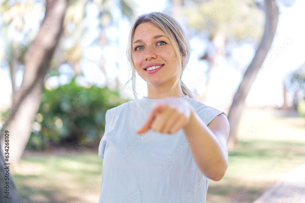 Young blonde woman at outdoors points finger at you with a confident expression Young blonde woman at outdoors points finger at you with a confident expression