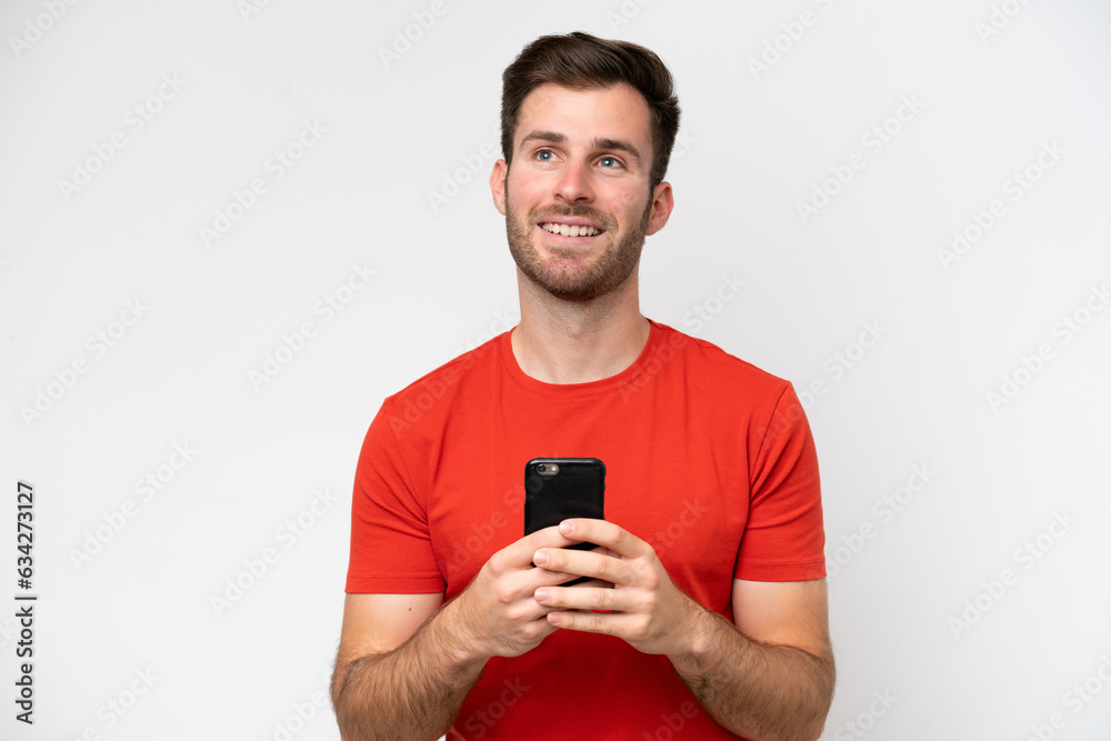 Young caucasian man isolated on white background using mobile phone and looking up Young caucasian man isolated on white background using mobile phone and looking up