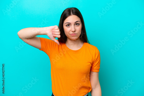 Young caucasian woman isolated on blue background showing thumb down with negative expression © luismolinero