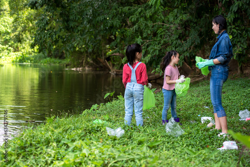Group student Charity and recycle plastic for environment.  People asia girl  and boy collecting garbage and plastic on the nature river to dumped into the trash for keep nature.