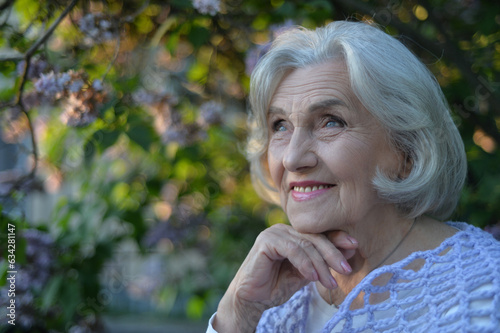 Close-up portrait of happy senior beautiful woman on background in spring park