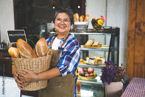 Portrait of a smiling senior Asian barista, hands on pockets, welcoming the customer in a cozy coffee shop.  Small business owner, family manage.