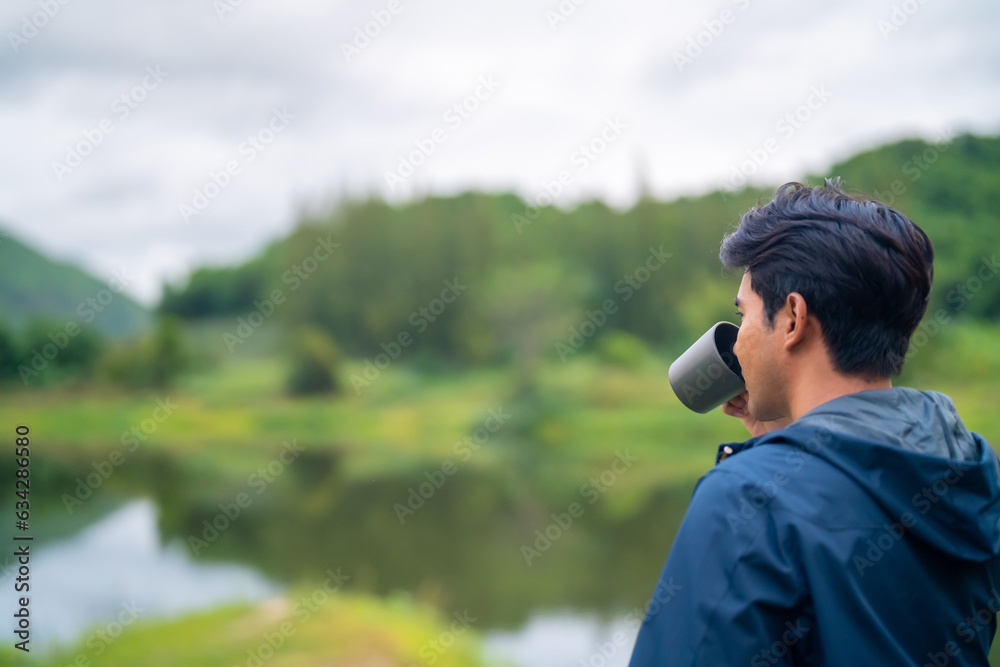 Asian man brewing and drinking hot coffee by the lake in morning. Handsome guy relax and enjoy outdoor lifestyle travel nature hiking and camping in forest mountain on summer holiday vacation trip. Asian man brewing and drinking hot coffee by the lake in morning. Handsome guy relax and enjoy outdoor lifestyle travel nature hiking and camping in forest mountain on summer holiday vacation trip.