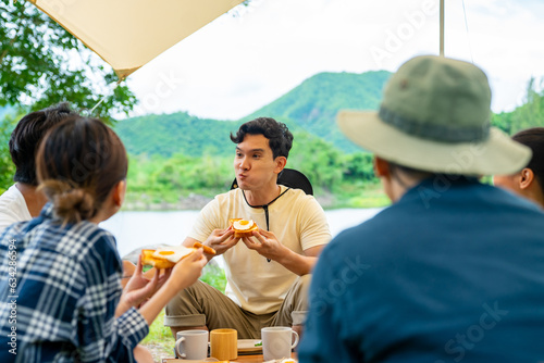 Group of Asian Man and woman friends having breakfast and drinking brewed coffee at camp in the morning. People enjoy and fun outdoor lifestyle travel nature and camping together on summer vacation.