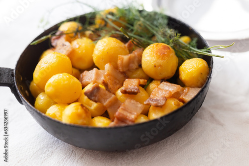 Fried new potatoes with bacon and dill in a frying pan
