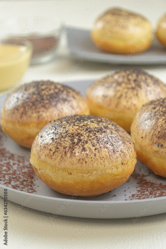 Donat tiramisu, sweet donuts with a variant of Tiramisu topping, served on a plate with a white background Donat tiramisu, sweet donuts with a variant of Tiramisu topping, served on a plate with a white background