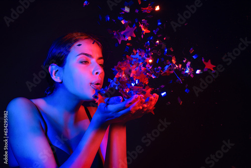 Sensual girl blowing confetti. Portrait of beautiful young lady on birthday valentines day. Sexy female model blow sparkles on birthday. Sensual woman celebrating birthday. Happy Birthday.