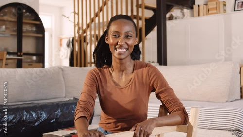 A Black Woman Building a Wooden Table and Looking at the Camera photo