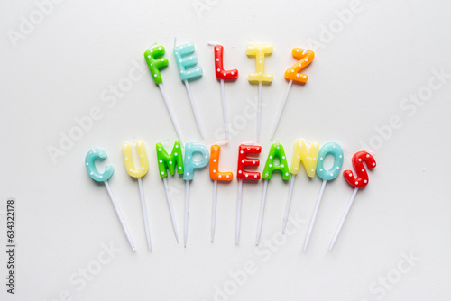 Translation: Happy birthday. The words in Spanish feliz cumpleaños formed with candle letters isolated over white with copy space.