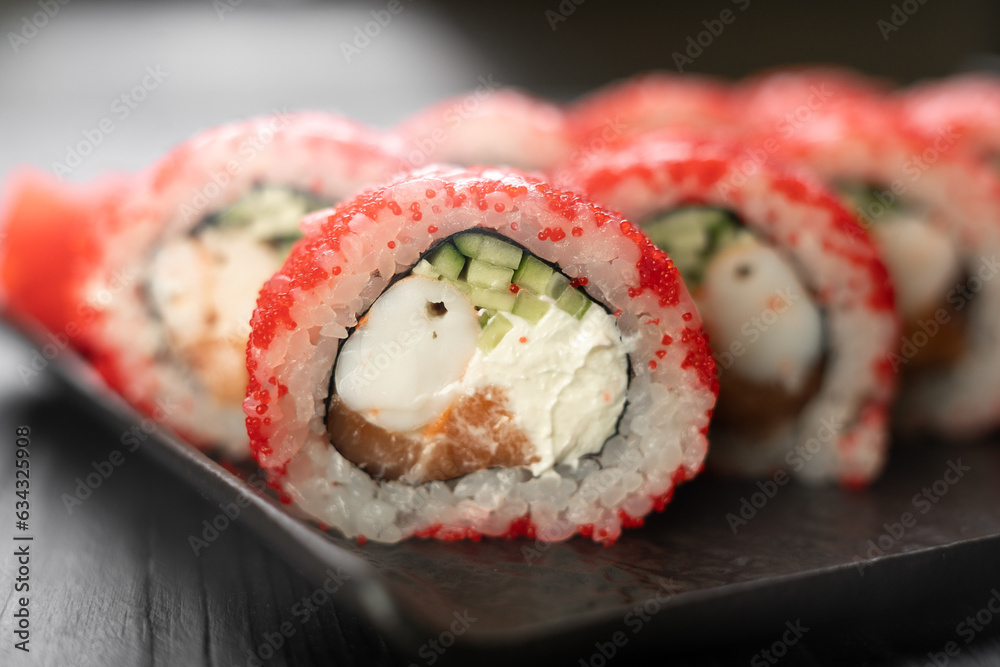 Sushi roll with shrimp, masago caviar, salmon, avocado and Philadelphia cheese on a black background Sushi roll with shrimp, masago caviar, salmon, avocado and Philadelphia cheese on a black background