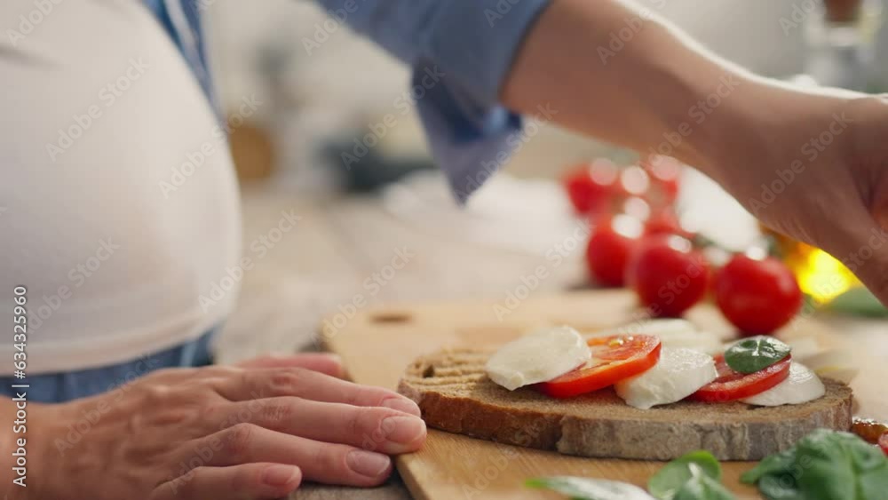 Basil, The Pregnant Girl is concentrating on making tomato toast in the home kitchen workspace. General angle young woman preparing toast with fresh cheese using new morning toast recipe, basil leaves Basil, The Pregnant Girl is concentrating on making tomato toast in the home kitchen workspace. General angle young woman preparing toast with fresh cheese using new morning toast recipe, basil leaves