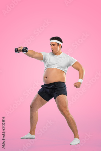 A funny fat man with dubbell isolated on pink background. Obesity and eating disorder. Concept for dietetics and fitness advertising in social networks. photo