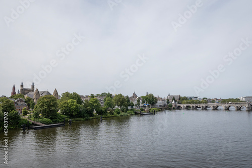 Rooftop of The Basilica of Our Lady religious Roman Catholic building landmark in Maastricht city Netherlands. Trees line the banks of the river Meuse with small wooden dock