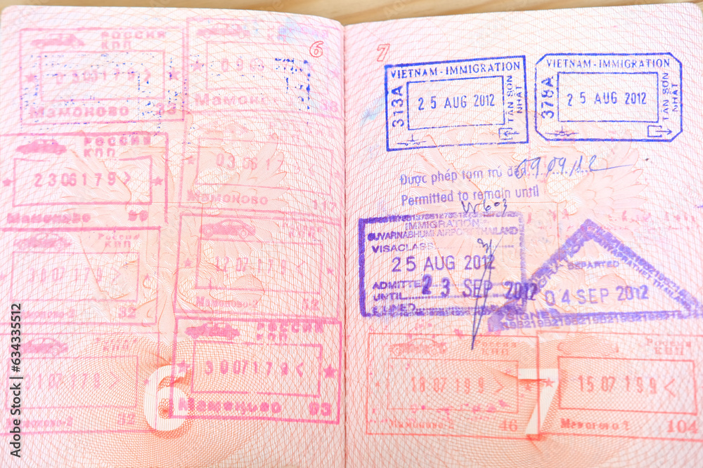 Fototapeta premium close up part of pages of foreign passport with foreign visas, border stamps, permits to enter countries, concept of traveling around the world, traveler's travel document