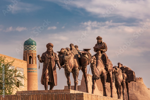 Sculpture of camels carrying goods along Silk Road and men in traditional dress, Khiva, Uzbekistan
