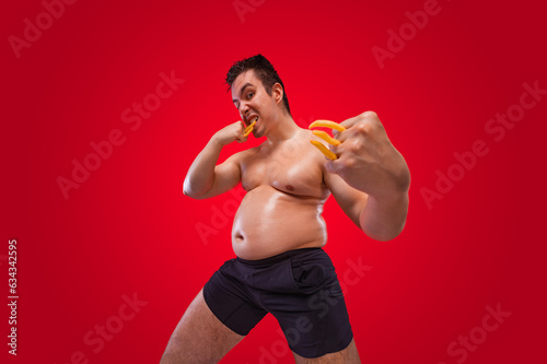 A funny fat man isolated on red background. Obesity and eating disorder. Concept for dietetics and fitness advertising in social networks. photo