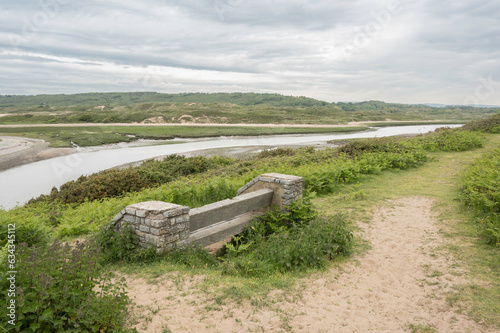 A bench, overlooking the river Ogmore in South Wales, towards the sand dunes of Merthyr Mawr. The day is cloudy. photo