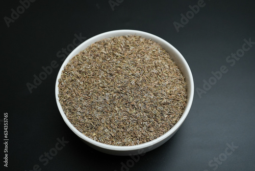 Dill seed in a white plate on a black background