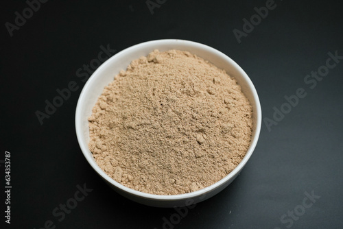 Ginger Root Powder on a white plate on a black background
