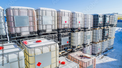 Plastic tanks on pallets. Containers for storage and transportation of liquids. Warehouse of plastic barrels. Cisterns are stored in snow. Tanks in metal crate. Tanks for chemical products