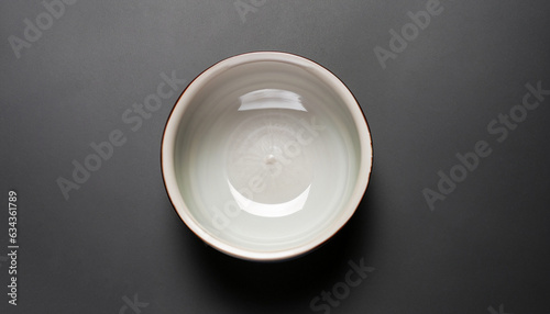 Ceramic bowl on black background, top view