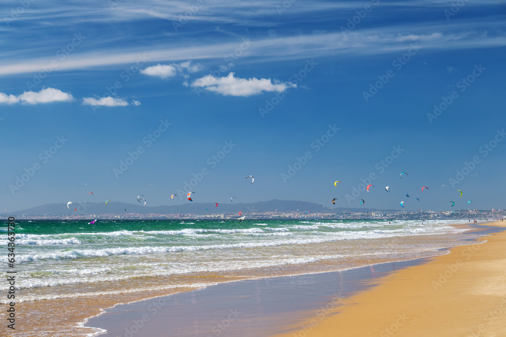 Kiteboarding kitesurfing kiteboarder kitesurfer kites on the Atlantic ocean beach at Fonte da Telha beach, Costa da Caparica, Portugal