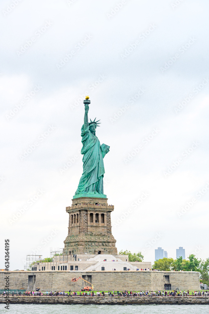 New York, New York, United States. August 07, 2023. Dramatic and detailed image of the Statue of Liberty with strong shades of green, sky with many clouds and very high resolution.