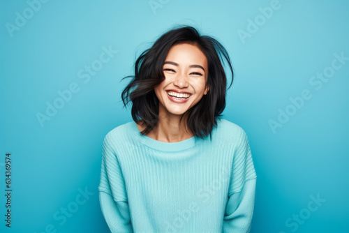 Smiling Asian Woman with a Cute Portrait on Blue Studio Background © bomoge.pl
