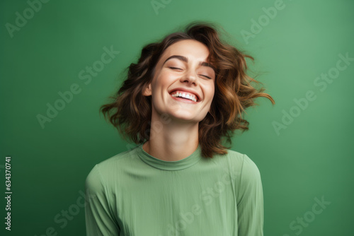 Smiling woman with a cute pose on a vibrant green studio background