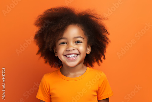 Joyful African American Girl with Vibrant Orange Studio Background © bomoge.pl