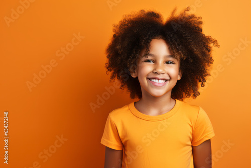 Joyful African American Girl with Vibrant Orange Studio Background © bomoge.pl