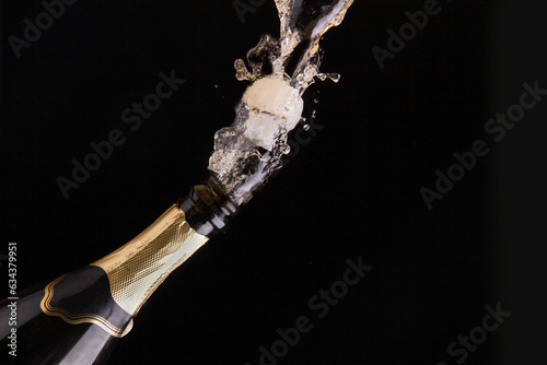 A cork mixed with splashes flies out of a bottle of champagne