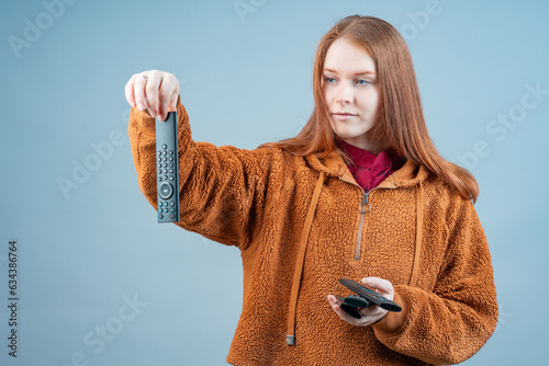 a woman contemptuously holds a remote control, a dirty remote control in her hands photo