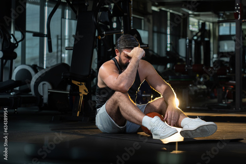 depress athletic caucasian man after practicing routine weightlifting and overtraining at modern gym, active fitness people suffer pain injury accident from workout weight training in dark sport club