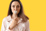 Young woman with spoon on yellow background, closeup