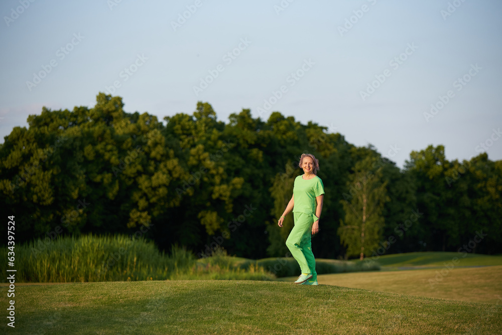 Adult energetic self-confident woman 50 years old, walking on the golf course